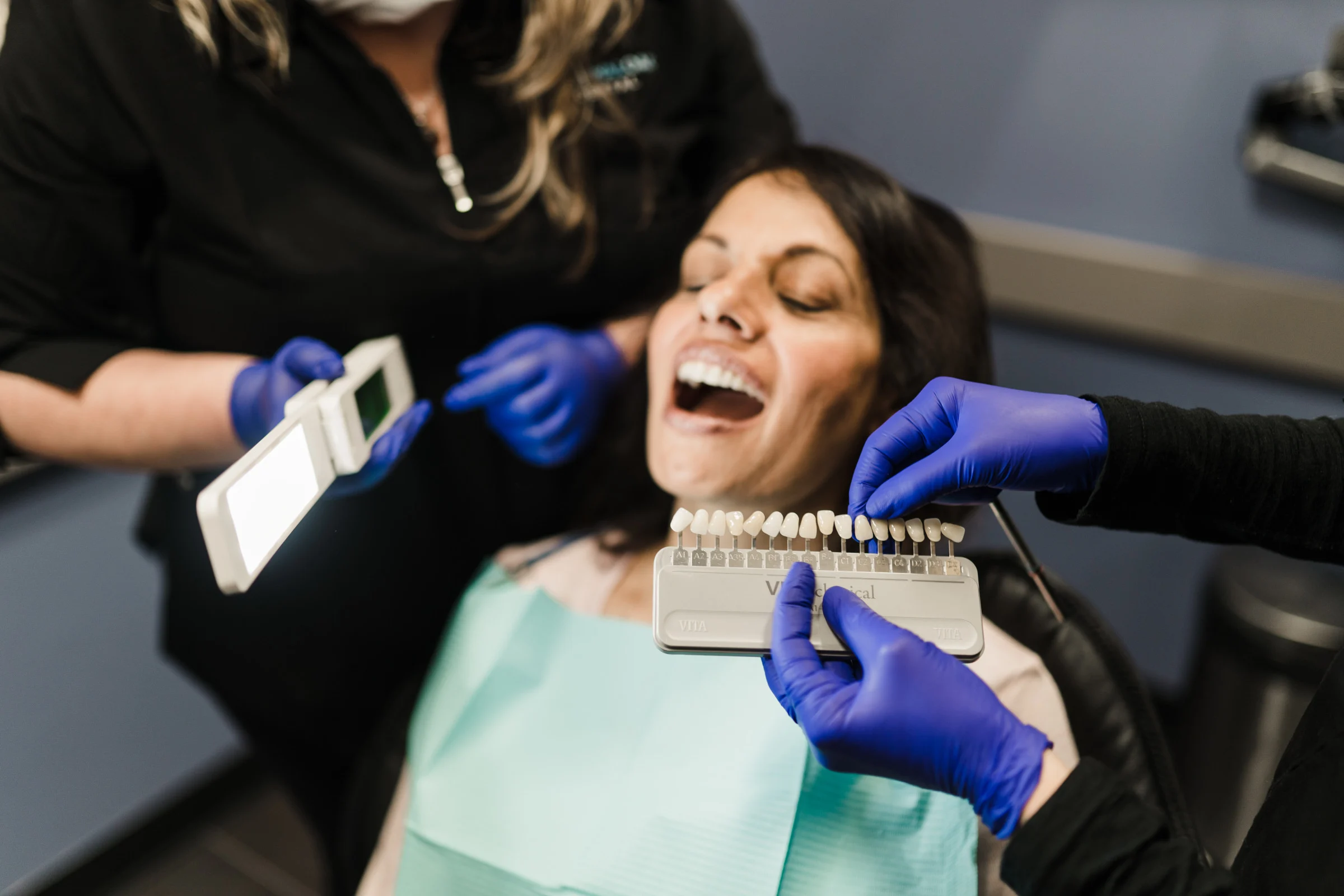 A dentist uses a tooth colour selector to determine a patients natural tooth colouration