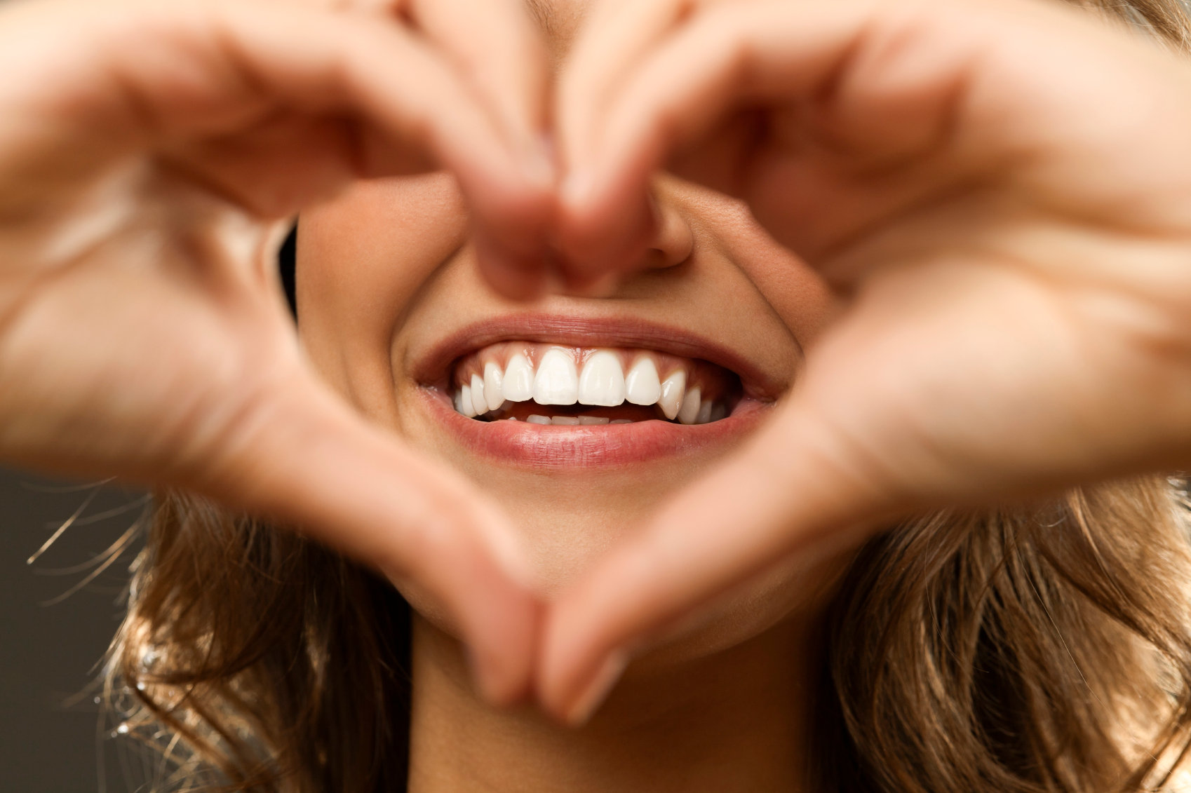 A patient smiles and makes a heart shape with her hands.