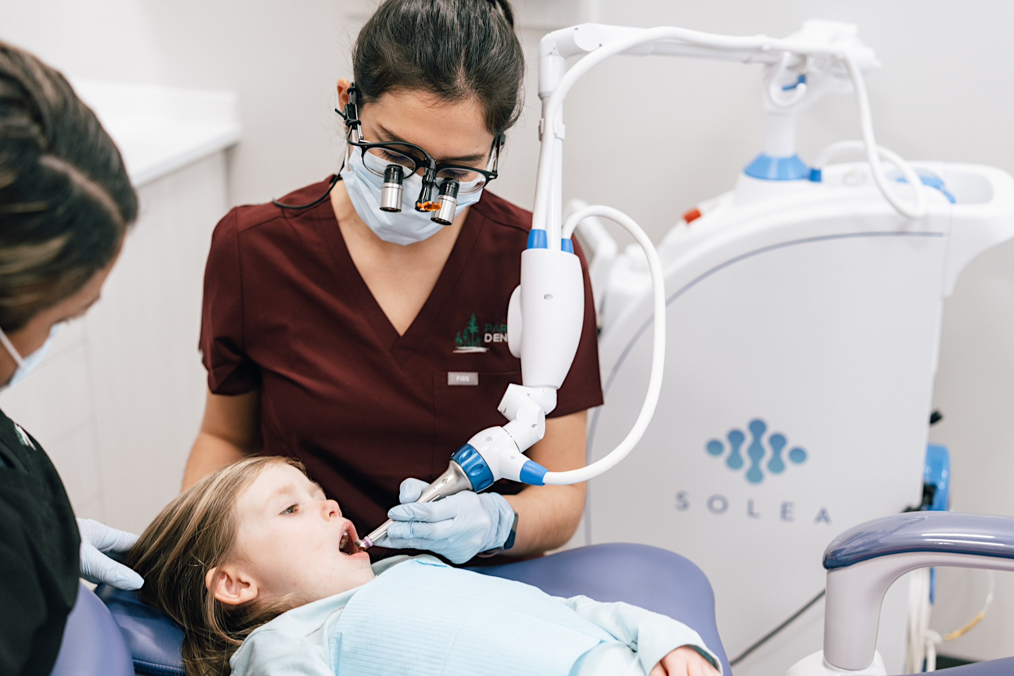 The dentist gently uses a dental laser with a child patient at Parkway Dental in Langford